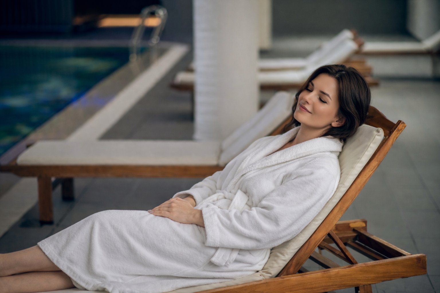 Woman relaxing poolside in a robe at the luxury spa retreat